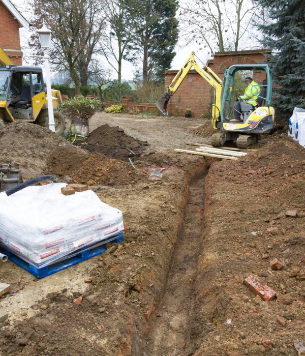 Buckingham, UK - December 02, 2016. Digger driver, digging a trench for drains on a UK building site